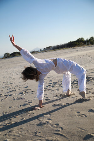 Blonde Girl With White Dress Dances On The Beach In Summerの写真素材