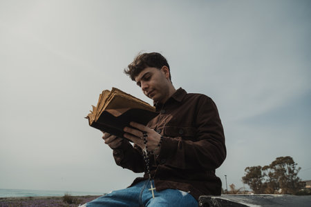 Christian Man Reading A Prayer On The Bible Book While On The Beachの写真素材