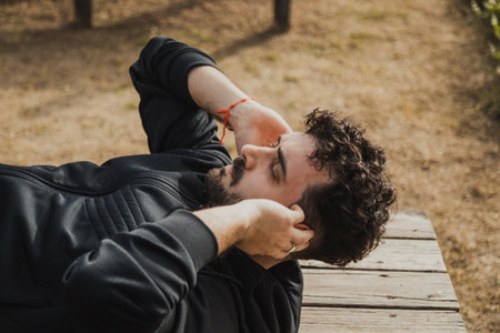 Man Relaxes on a Wooden Bench in the Outdoor Park