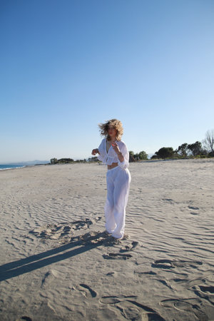 Blonde Girl With White Dress Dances On The Beach In Summer Near The Seaの写真素材
