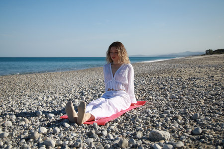 Young Woman Trains Her Feet Before Dancing on the Beach Near the Seaの写真素材