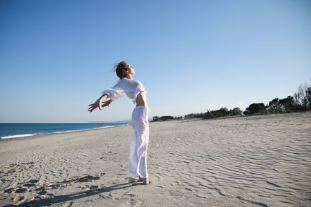 Young Italian Woman Dances On The Beach In Summer Near The Oceanの写真素材