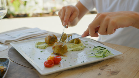 Man Using Fork And Knife To Cut The Gourmet Fish Gratin Dish At The Resort