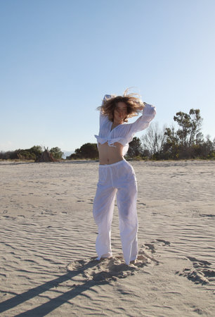 Young Woman Dances On Sicily Beach In Summer Vacation With White Shirtの写真素材