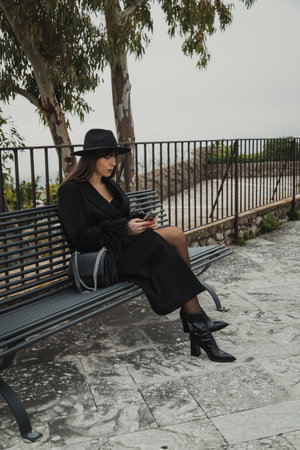 Elegant Woman Relaxing On The Park Bench Holding Her Sunglassesの写真素材