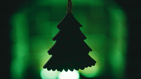 Silhouette of a small Christmas tree shape in front of a green fireplaceの写真素材