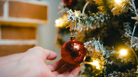 Hand caressing a red Christmas ball on a treeの写真素材