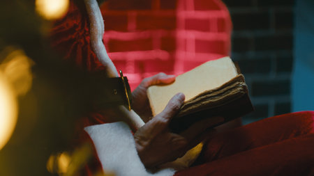 Santa Claus Reads a Book by the Christmas Fireplaceの写真素材