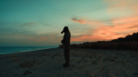 Soldier in silhouette at sunset on a beach