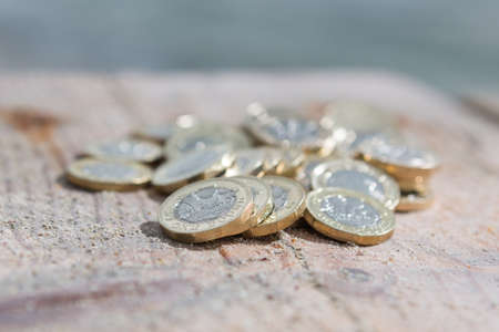 Pile of New British Pound Coins on the wood. New Pounds in a Warm Sunrise Light.の写真素材