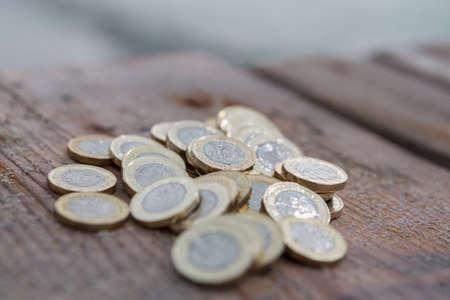 Pile of New British Pound Coins on the wood. New Pounds in a Warm Sunrise Light.の写真素材