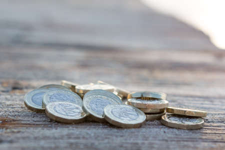 Pile of New British Pound Coins on the wood. New Pounds in a Warm Sunrise Light.の写真素材