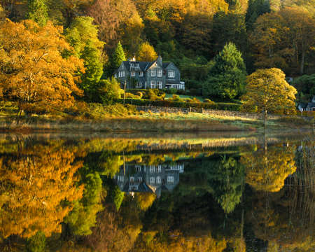 Rural country house reflecting in a calm lake with stunning Autumn colours. Taken at Rydal Water in the English Lake District.の写真素材