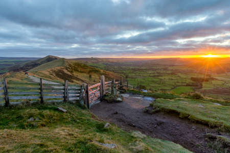 Countryside gate bathed in morning sunlight with rural view in background and sun peaking above...
