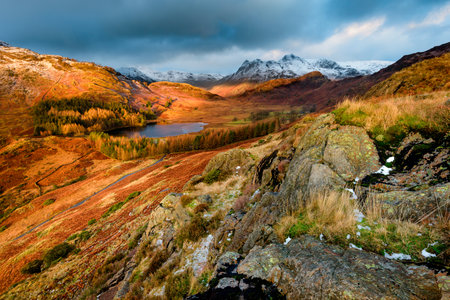 Ultra Wide View Of Dramatic Landscape Blea Tarn With Snow On Langdale Pikes And Dark Moody Clouds. Lake District, UK.の写真素材