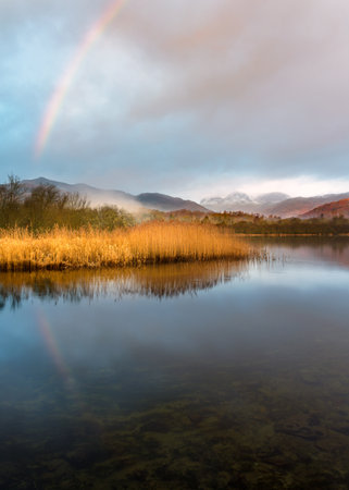 Rainbow Reflection In Calm Lake On Peaceful Morning At Elterwater, Lake District National Park, UK.の写真素材