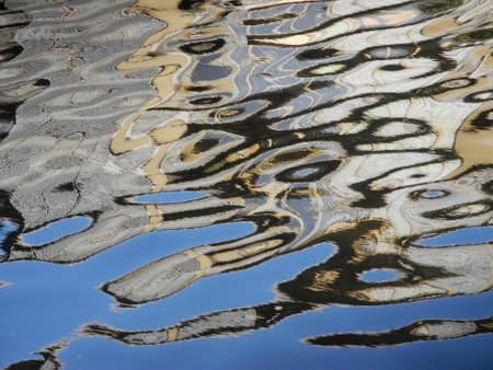 A wavy reflection of a building caught in the water causing an abstract pattern which is reminiscent of the ovoids of Northwest Coast Native art.の写真素材