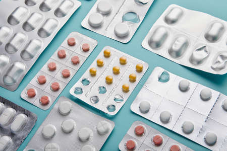 Different medicine pills wrappers over sky blue background. Top Viewの写真素材
