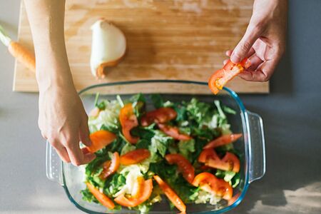 Woman making a healthy salad in a glass recipient with different ingredientsの写真素材