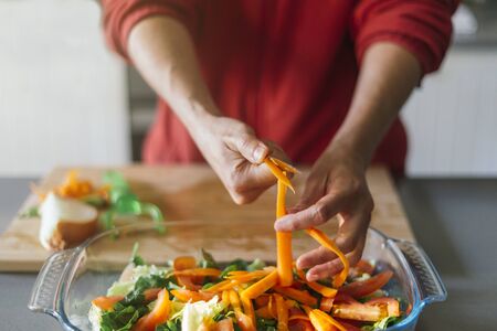 Woman cutting carrots and putting them in a salad with her handsの写真素材