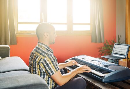 Man playing piano while taking online lessonsの写真素材