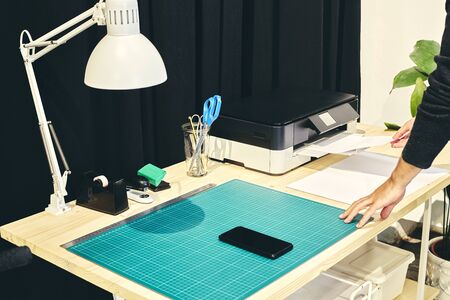 Office space with one person at the printer and a mobile phone on the tableの写真素材