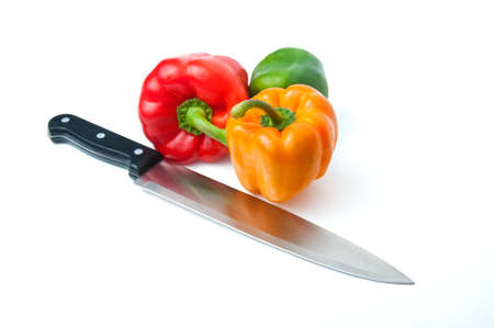 Three red, green and yellow peppers with a knife on a white backgroundの写真素材