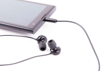 Black smartphone with headphones on white backgroundの写真素材