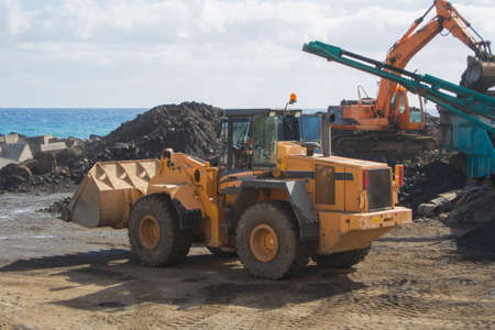 Bulldozer in a quarry with a conveyor belt and an excavatorの写真素材