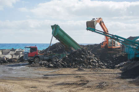 Truck unloading its cargo of land near the seaの写真素材