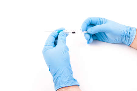 An arm with blue glove holding a syringe to vaccinate
