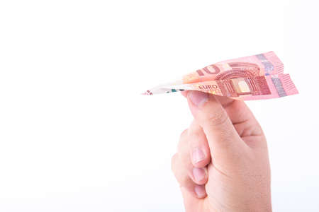 Paper plane made with a bill of 10 euros and a hand getting ready to make it fly on white backgroundの写真素材