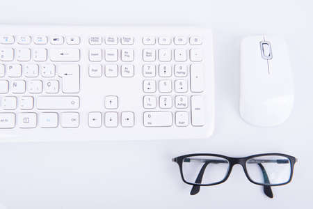 Black glasses with a wireless keyboard and mouse on a gray tableの写真素材