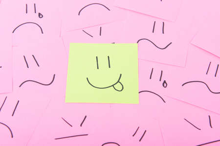 Yellow post it with happy face on red posits with sad facesの写真素材