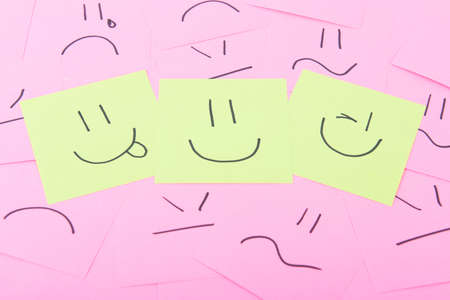 Yellow post it with happy face on red posits with sad facesの写真素材