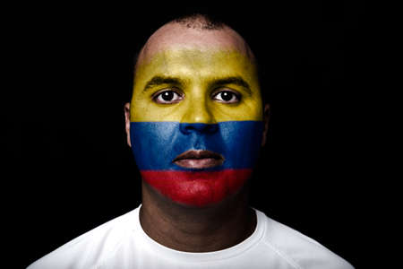 Man with Colombia flag painted on her face on black backgroundの写真素材