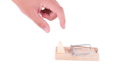 Hand trying to catch a piece of cheese on a mousetrap on white background