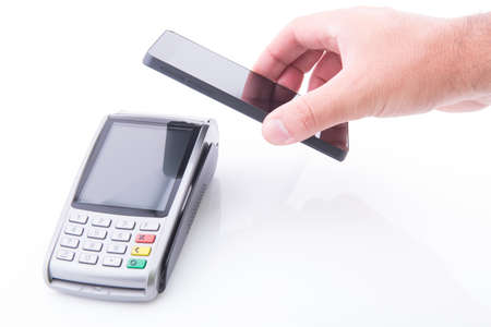 Hand with a smartphone making a payment on a POS terminal on white background