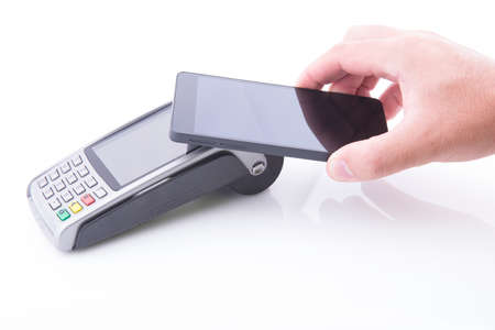Hand with a smartphone making a payment on a POS terminal on white backgroundの写真素材