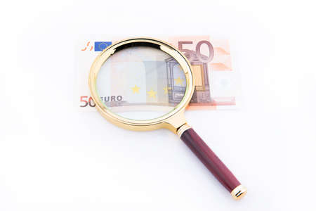 Fifty euro banknote with magnifying glass over white background