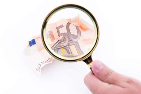 Crumpled fifty euro banknote with magnifying glass over white background