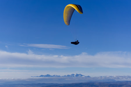 Paraglider flying in the blue sky with white clouds.の写真素材