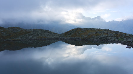 Mountain reflection in a lake with clouds in the background, Tatra Mountains, Hiking through...