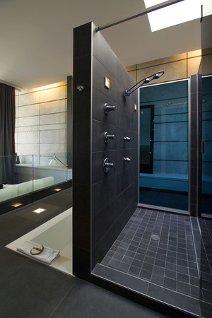 Shower with dark grey ceramic walls and floor near the bathの写真素材