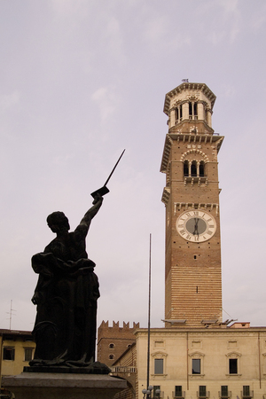 A statue pointing a sword to the clock tower in Vincenza Italyの写真素材
