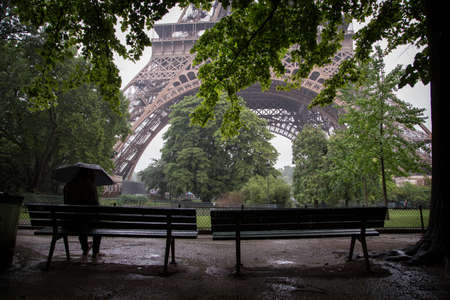 A woman sitting on the bench waiting for the rainの写真素材