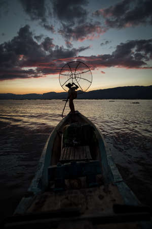 Intha fisherman posing with conical nets at sunset, Inle Lake in the Nyaungshwe Township part of Shan Hills in Myanmar Burmaの写真素材