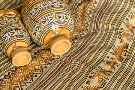 Moroccan ceramic and leather drums, lying on coloured textiles. Natural light. Traditional music...