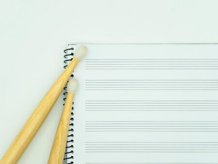 Top view Wooden sticks on a music notebook with staves. Concept music.