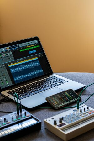 Close up view of fm synthesizer, sampler, smartphone with modular synthesizer and laptop with open audio editor Electronic music concept. Vertical image.の写真素材